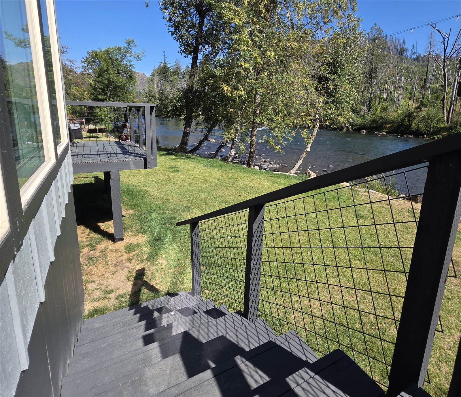 Deck and steps leading down to the riverside lawn and McKenzie River at The River Front House